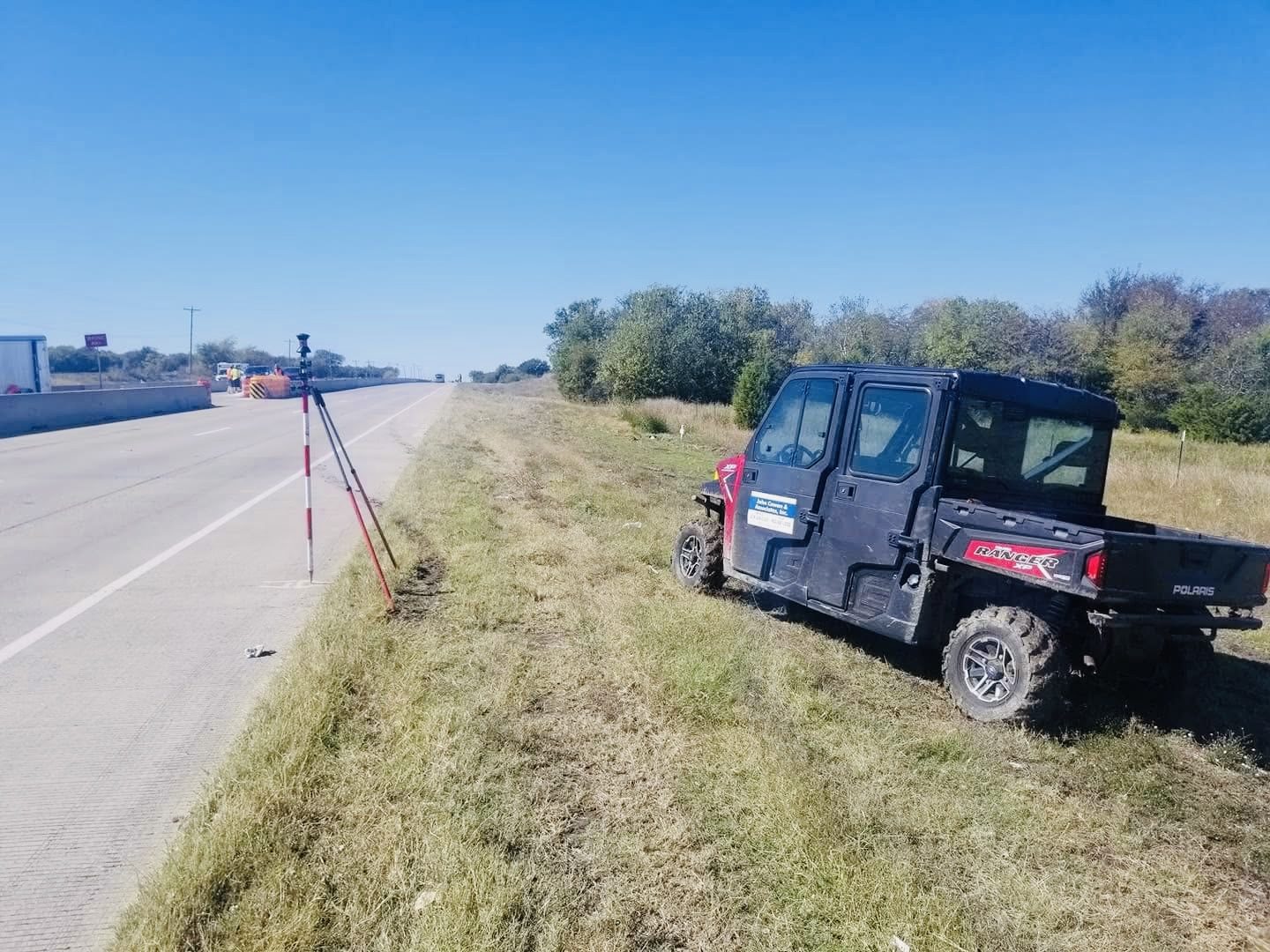 John Cowan & Associates Polaris Ranger estacionado en un hombro de carretera con un poste de prisma rojo y blanco sobre un bipod en el borde del pavimento