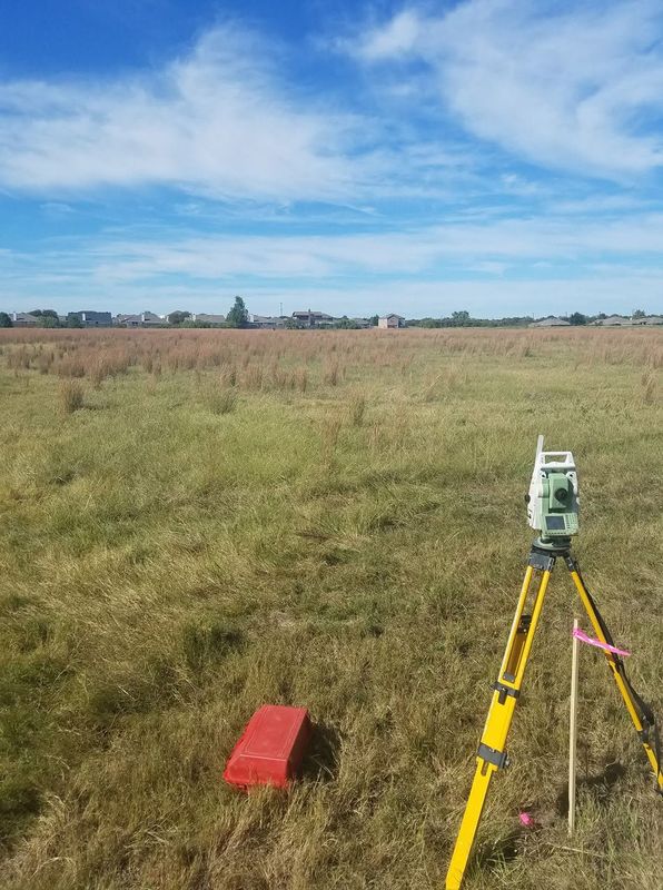 Survey instrument on a tripod in a grassy field